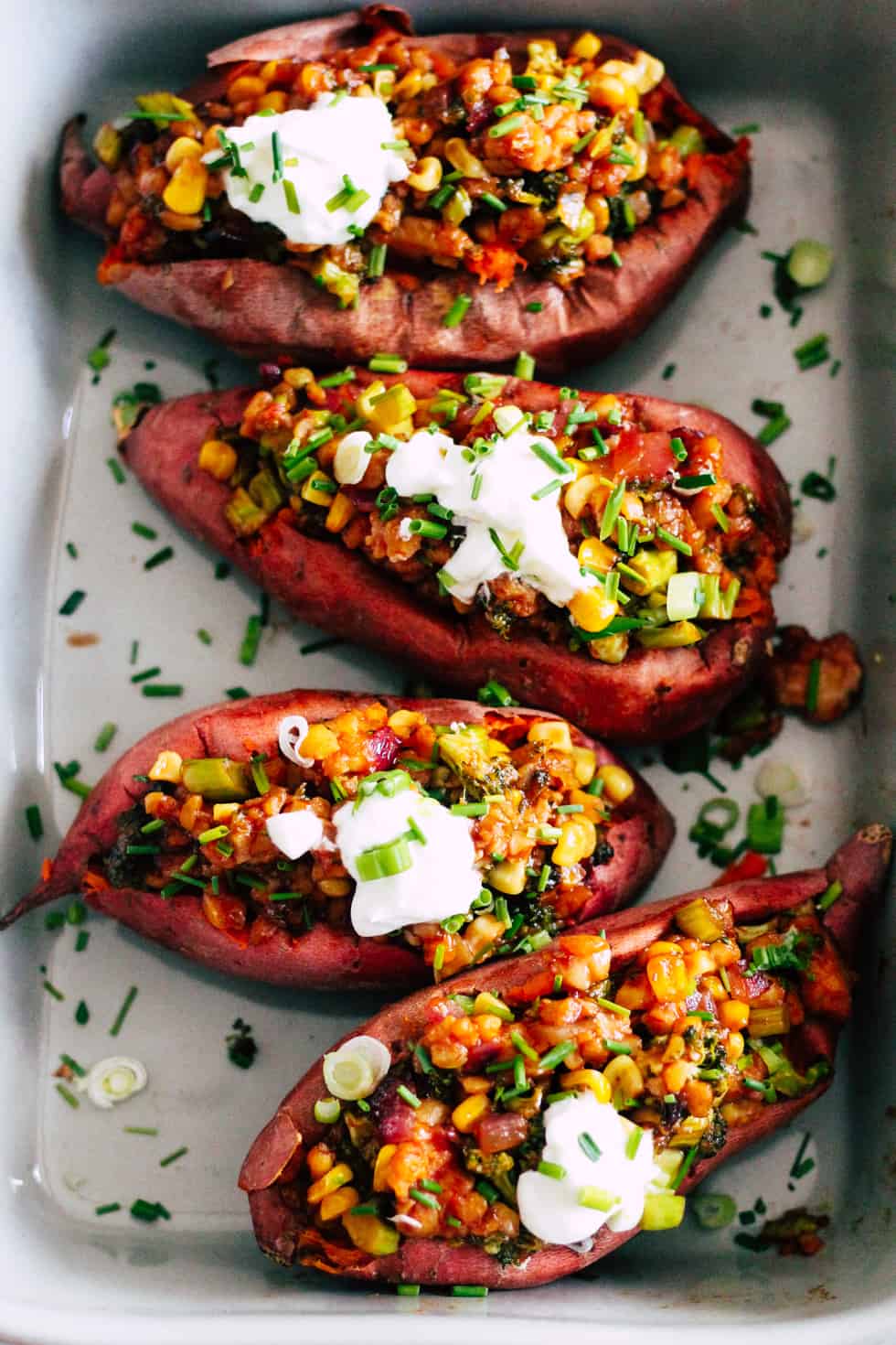 Baking dish with four loaded sweet potatoes.