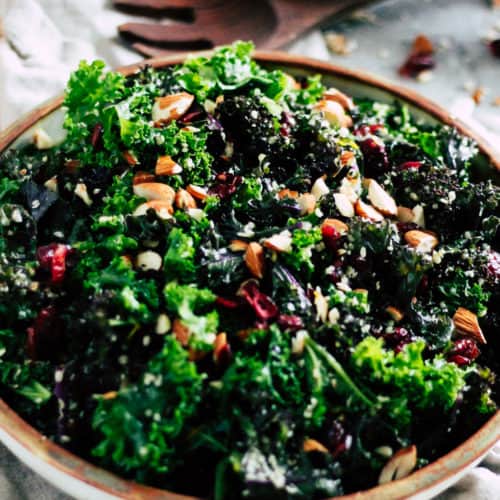 Make-ahead kale salad in ceramic dish with cream napkin.