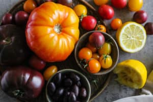 Horizontal image of multicolor heirloom tomatoes with cherry tomatoes and kalamata olives.