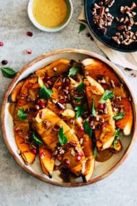Roasted squash in ceramic dish with toasted pecans and yellow curry sauce.