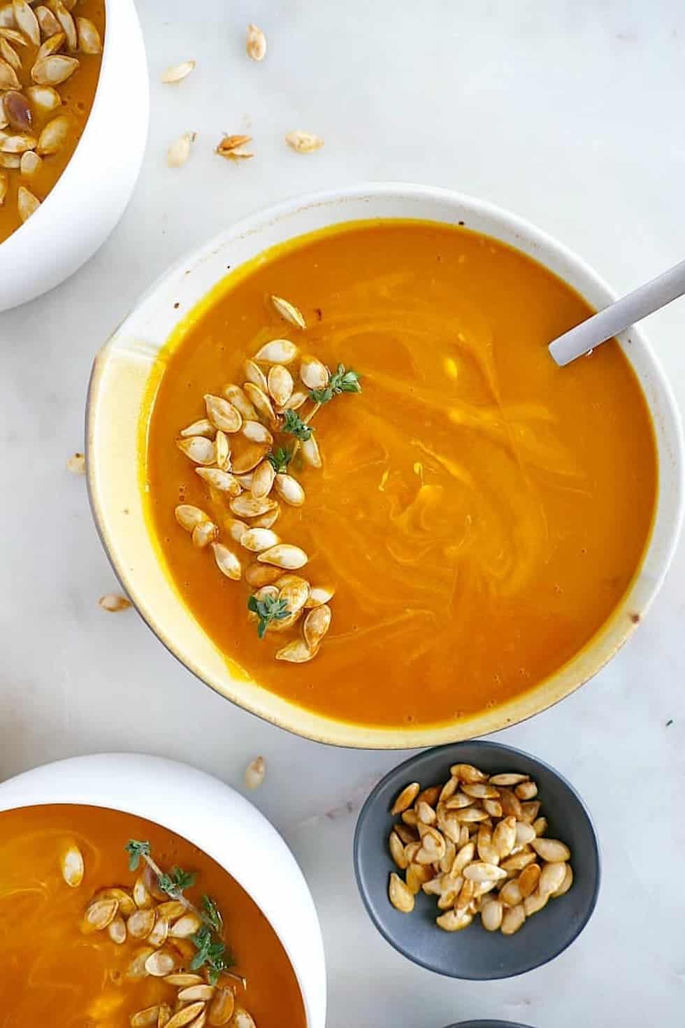 Orange squash soup in yellow ceramic bowl.
