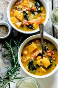 Vegan soup recipes, including vegetable soup in white bowls with rosemary.