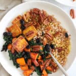 Baked Tofu Bowls with sweet potatoes and kale in white bowl with cream napkin.
