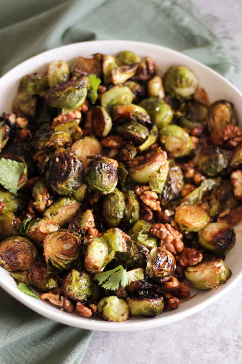Crispy roasted Brussels sprouts in white dish with green napkin.