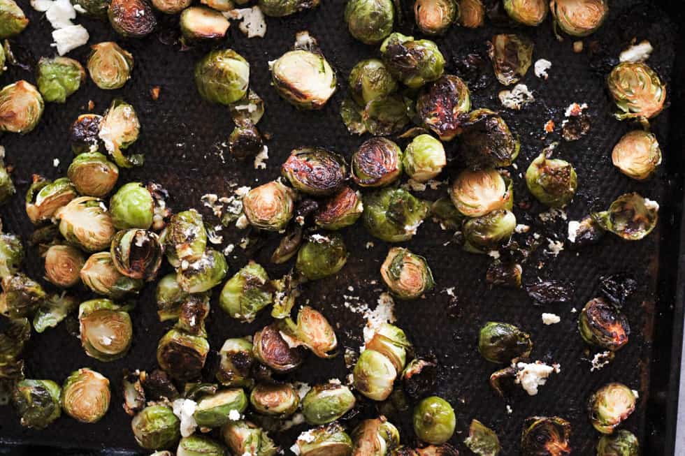 Crispy roasted Brussels sprouts and goat cheese on baking sheet.