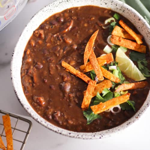 Black bean soup in white bowl with Instant Pot.