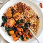 Fall-inspired tofu sweet potato bowl with kale, pecans, and farro.