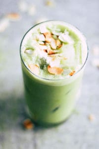 Iced Matcha Latte with coconut against grey background.