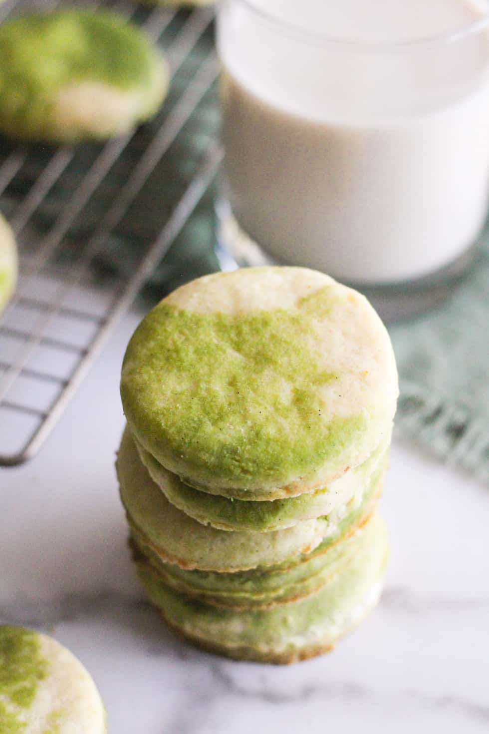 Stack of green tea cookie with glass of milk.