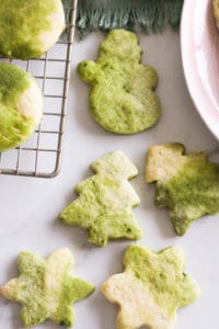 Matcha sugar cookies in Christmas shapes on white marble.