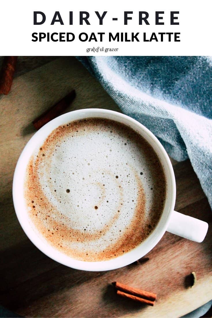 Cinnamon swirl latte on wood board with text that reads, "Dairy-Free Spiced Oat Milk Latte."