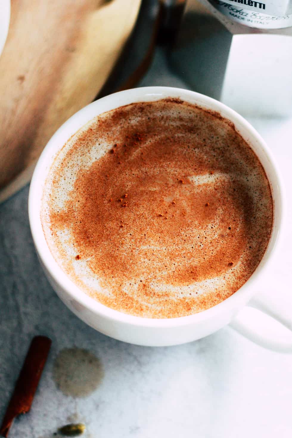 Oat Milk Latte in white mug with espresso maker behind it.