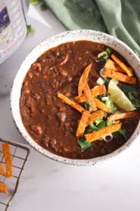 Instant Pot Black Bean Soup with tortilla strips in white ceramic bowl.