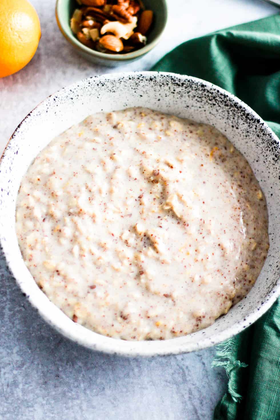 Bowl of oatmeal on gray counter with Meyer lemon and nuts.