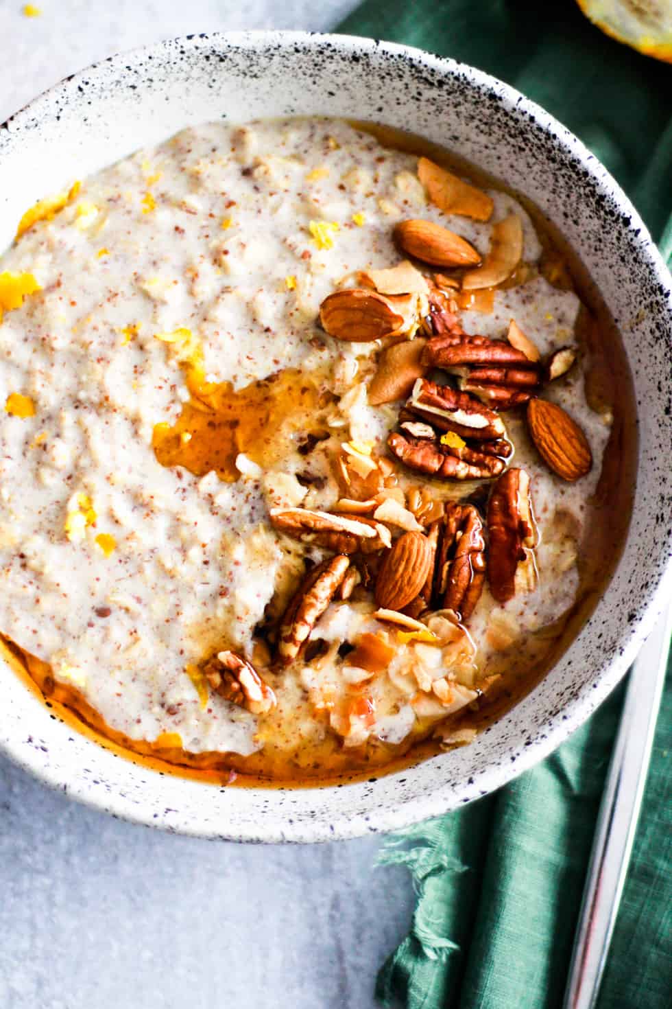 Bowl of vegan lemon oatmeal topped with nuts and maple syrup.