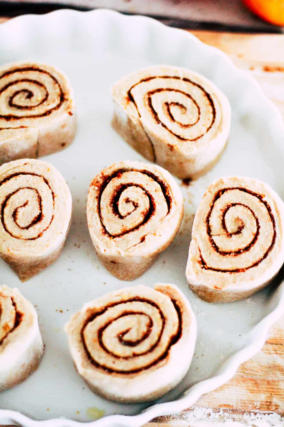 Uncooked cinnamon rolls in a white baking dish.