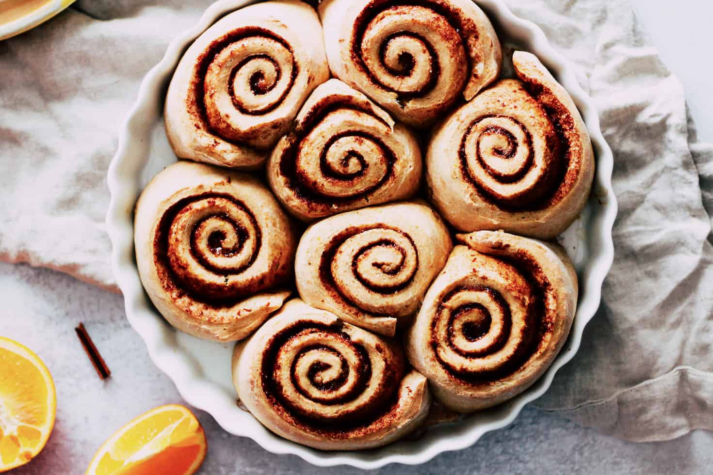 Horizontal image of cinnamon rolls in a white, round baking dish.