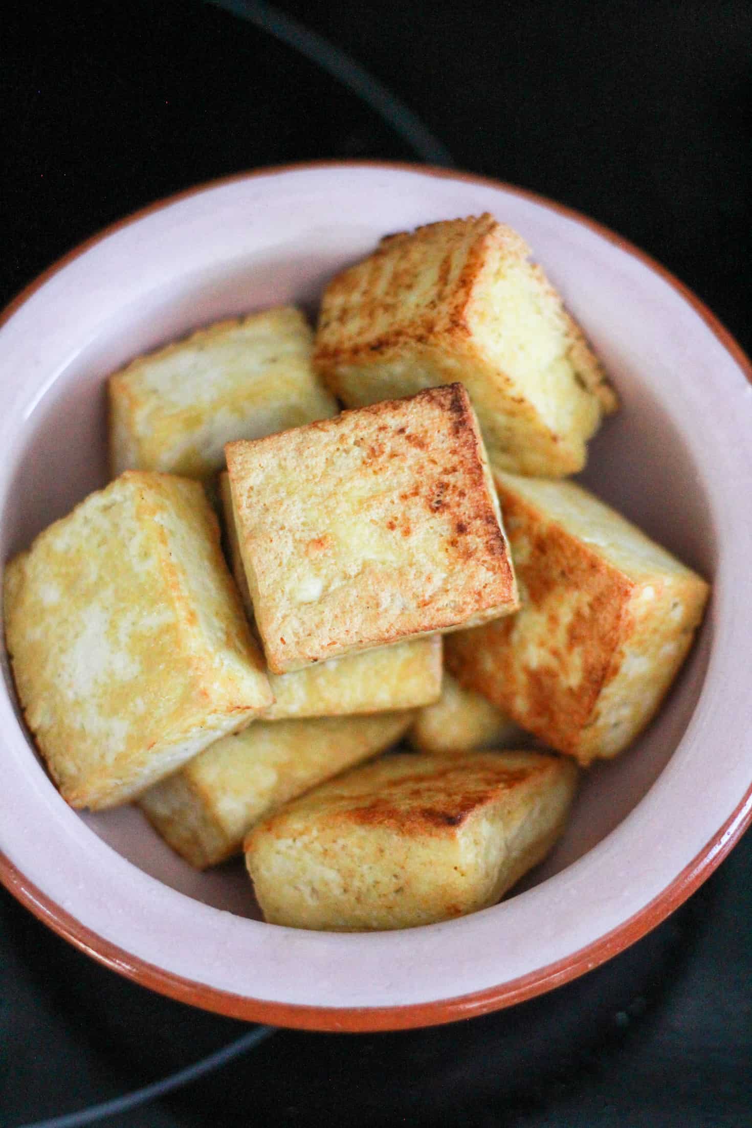 Pan-fried tofu in a pink bowl.
