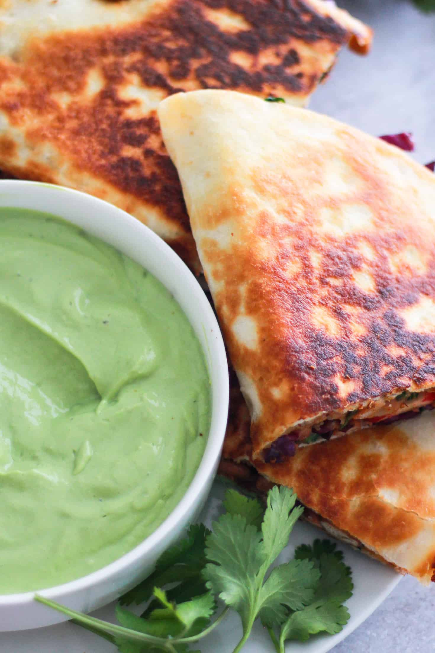 Bean quesadilla on a plate with avocado dipping sauce.