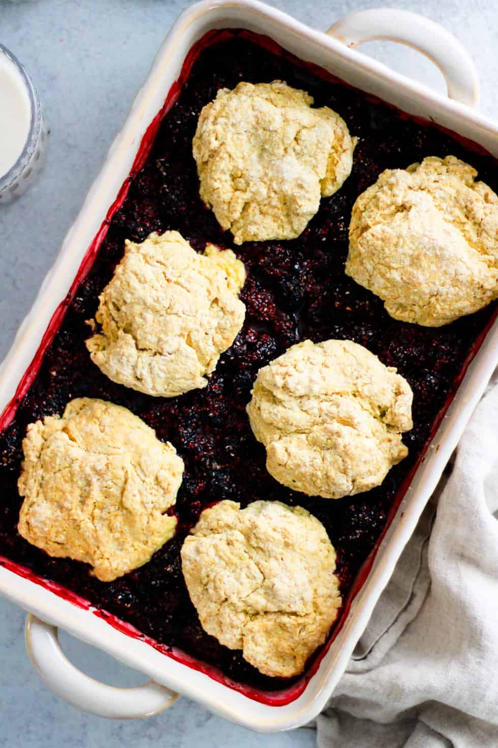 Berries covered with whole wheat biscuit topping in a white baking dish.