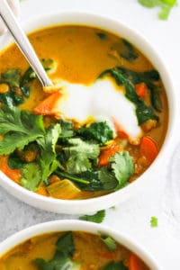 Vegan Turmeric Soup in white bowls with cilantro and yogurt.
