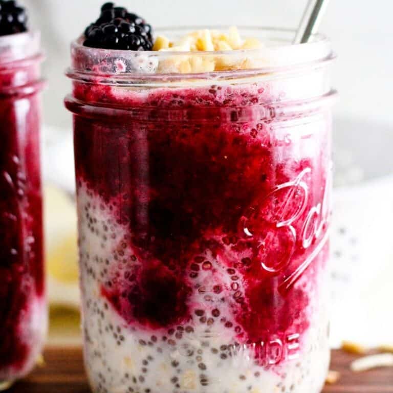 Overnight oats with blackberries, chia seeds, coconut, and nuts in a glass jar.
