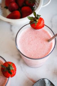 Dairy-free strawberry milkshake with fresh strawberries on white background.