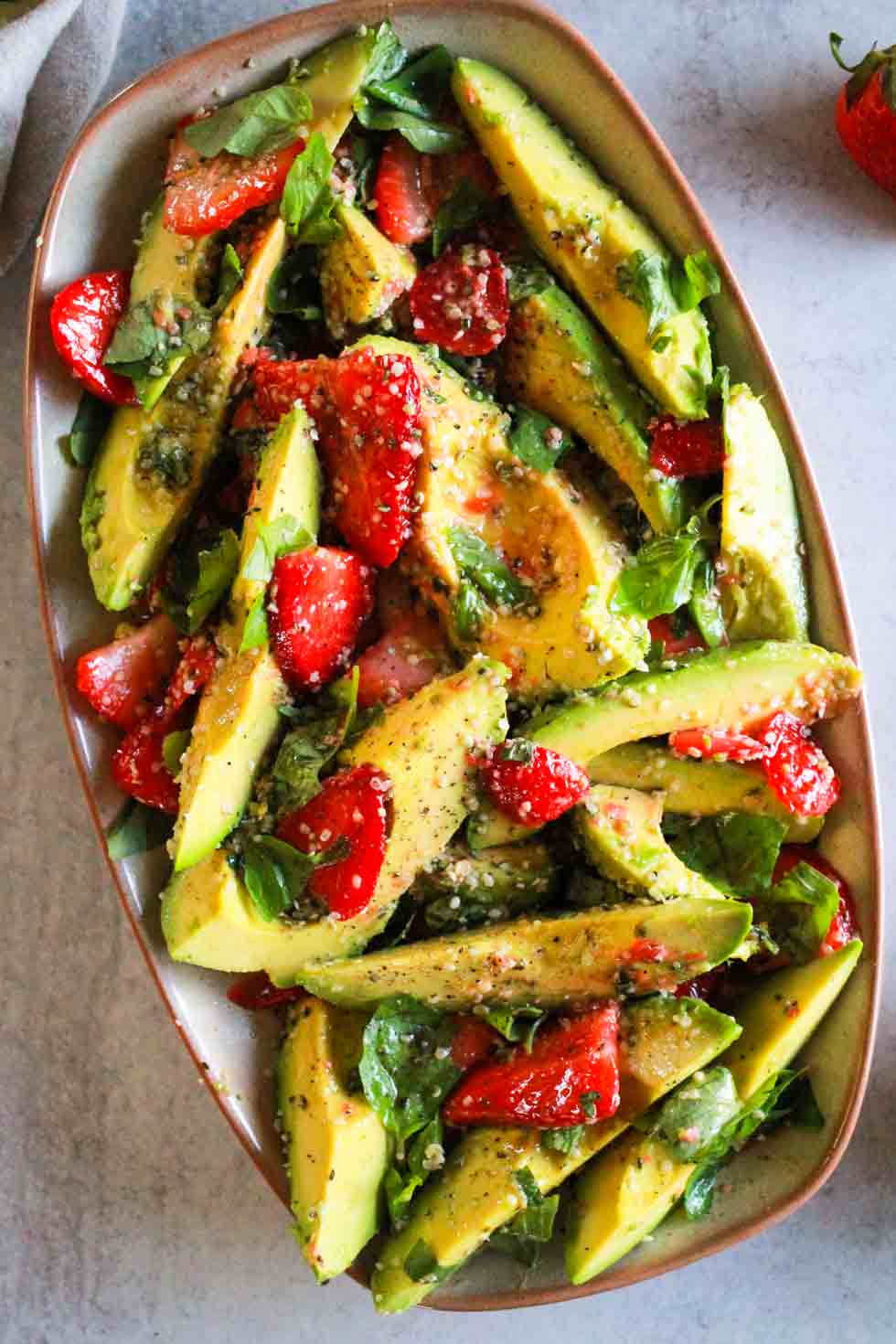 Overhead image of strawberry avocado salad on rectangular platter.