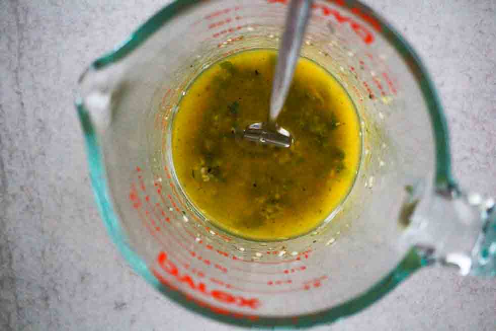 Lemon dressing in a glass measuring cup.