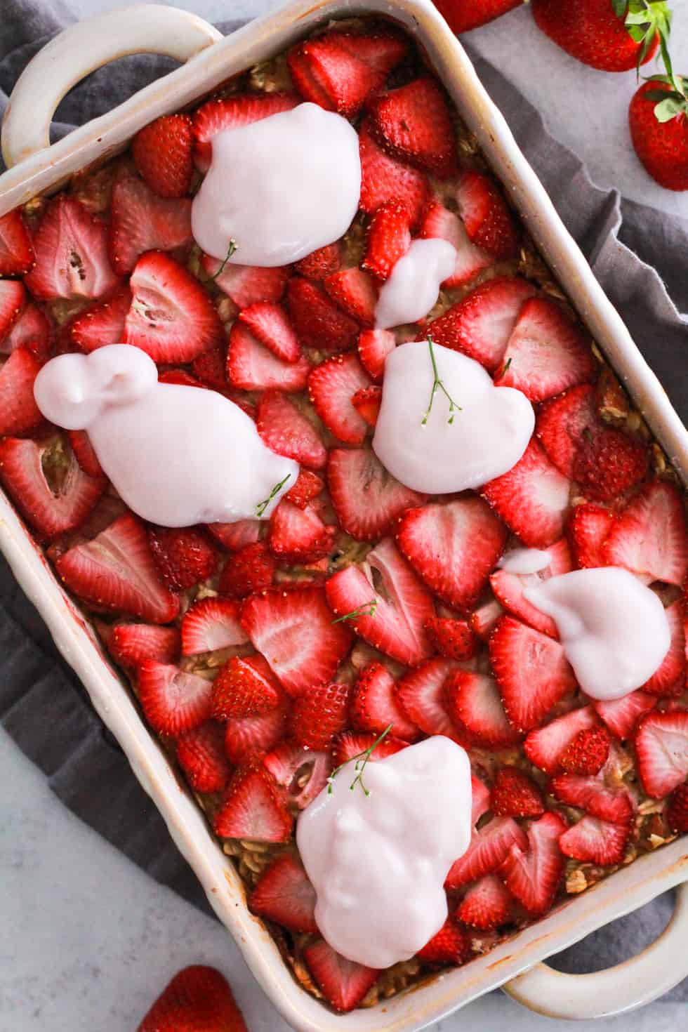 Overhead image of vegan baked oatmeal topped with strawberries and yogurt alternative.