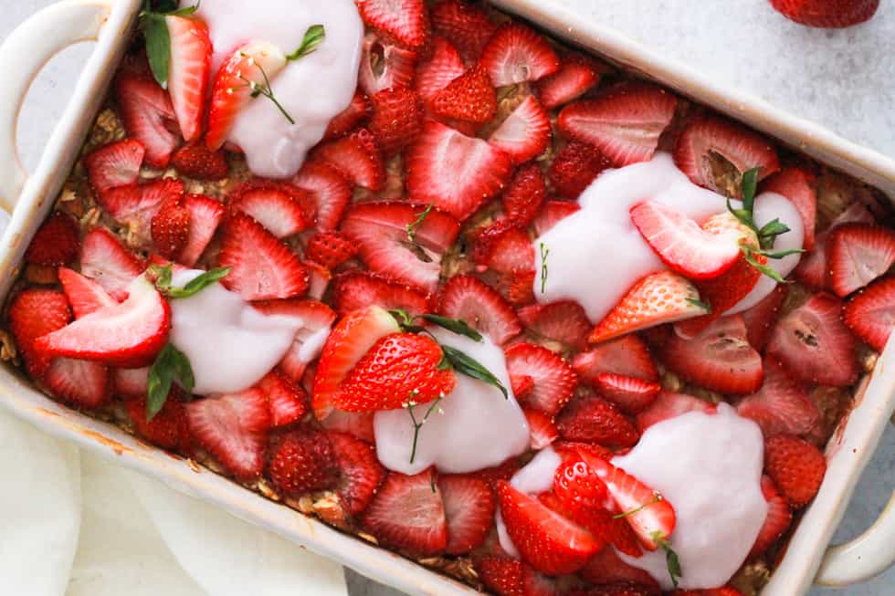 Horizontal image of vegan baked oatmeal topped with strawberries and yogurt.