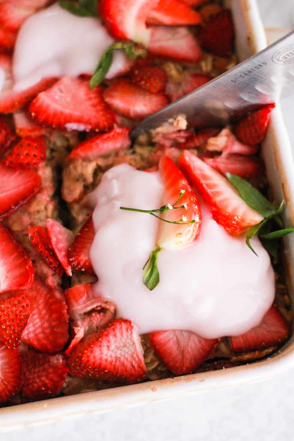 Closeup shot of knife cutting into strawberry baked oatmeal.
