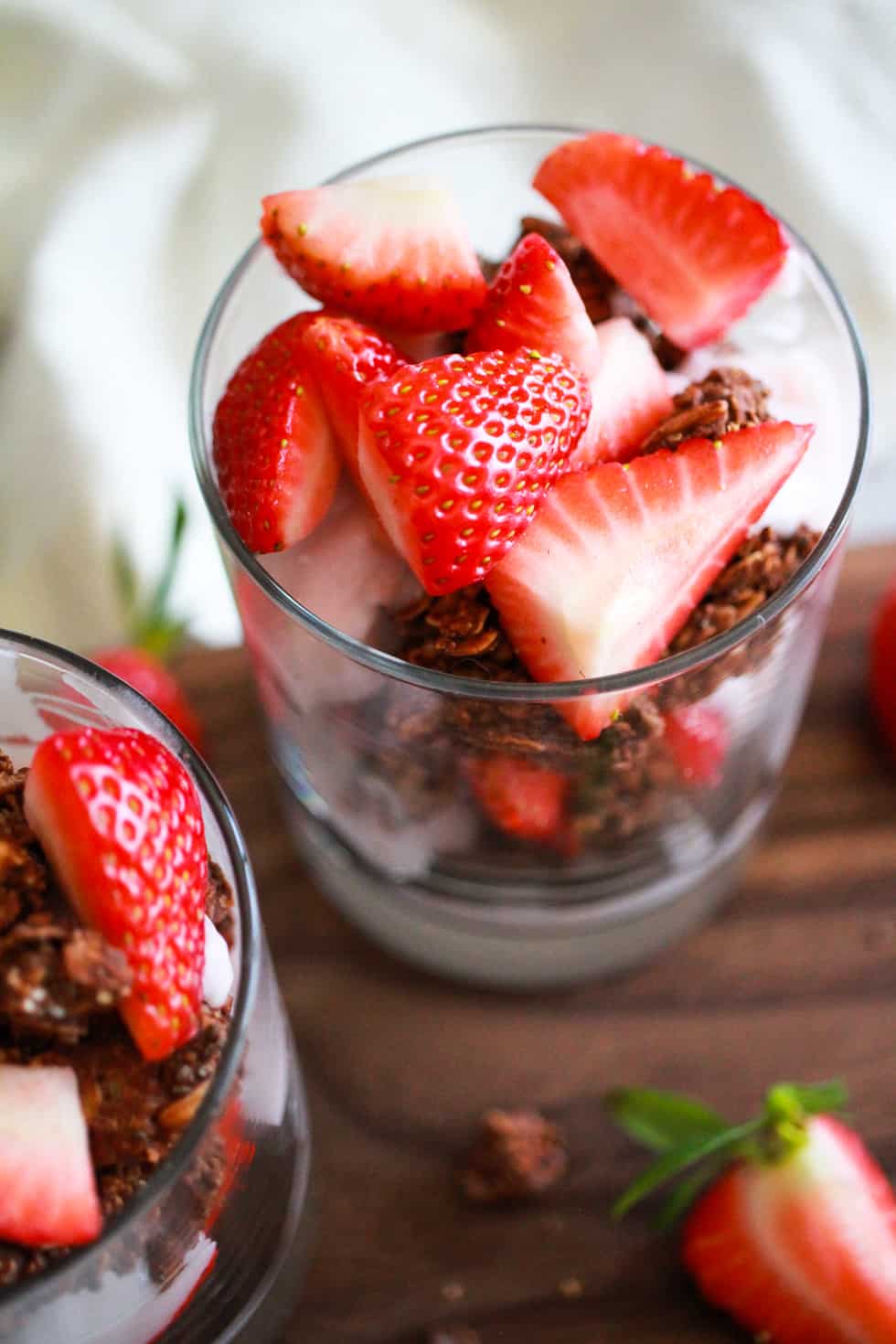 Strawberry yogurt parfait in a glass on wood board.