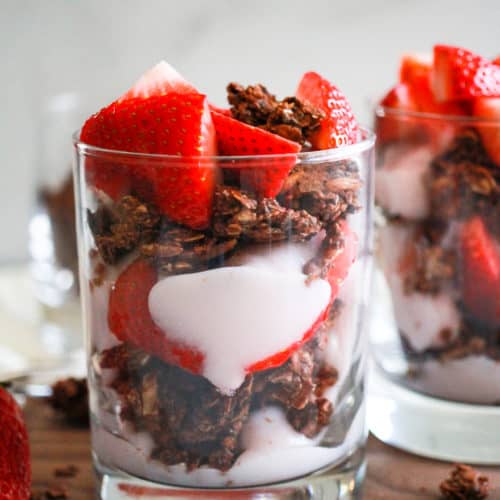 Vegan strawberry yogurt parfait in glass with chocolate granola.