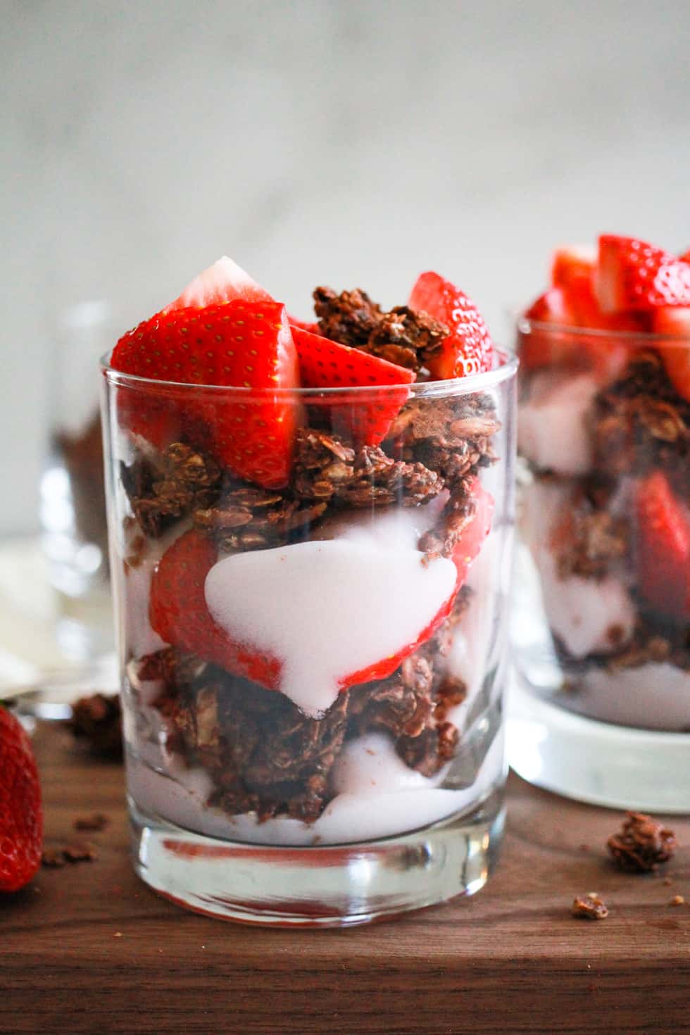 Vegan strawberry yogurt parfait in glass with chocolate granola.