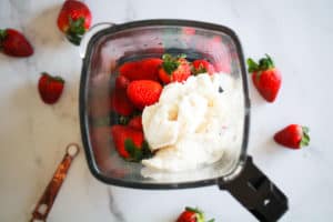 Blender filled with fresh strawberries and dairy-free ice cream.