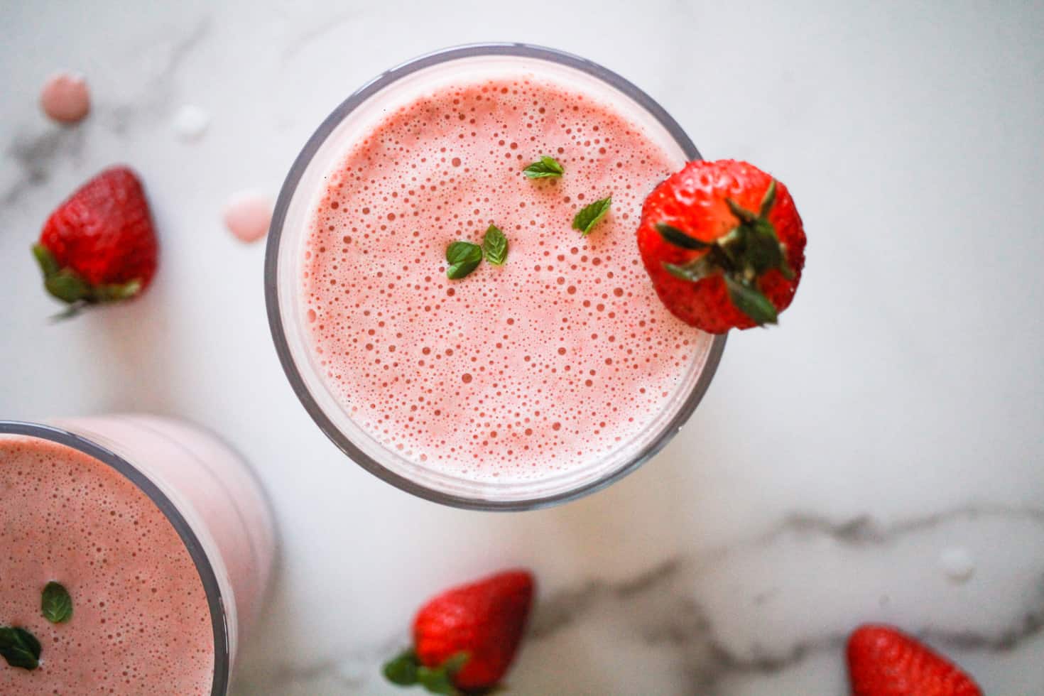 Horizontal overhead image of dairy-free milkshake topped with mint leaves and strawberry.