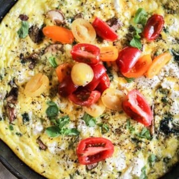 Egg frittata with mushrooms and goat cheese topped with tomatoes.