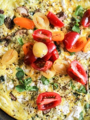 Egg frittata with mushrooms and goat cheese topped with tomatoes.