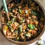 Pearl couscous with chickpeas and golden raisins in a wood bowl.