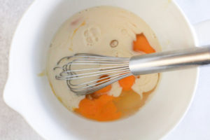 Eggs and milk being whisked together in a white bowl.