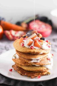 Tall stack of pumpkin pancakes with fruit and yogurt
