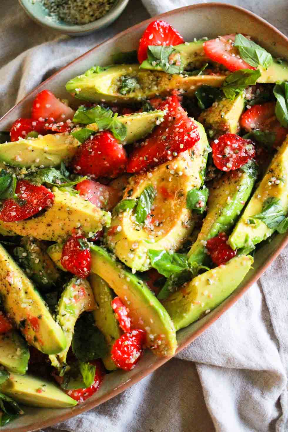 Strawberry avocado hemp salad on a rectangular platter with linen napkin.