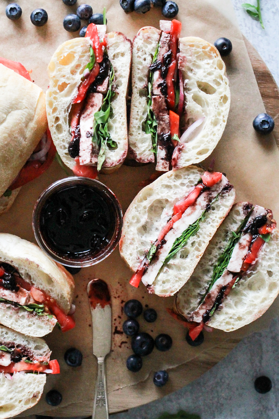 Overhead image of sliced sandwiches on a wood serving board.