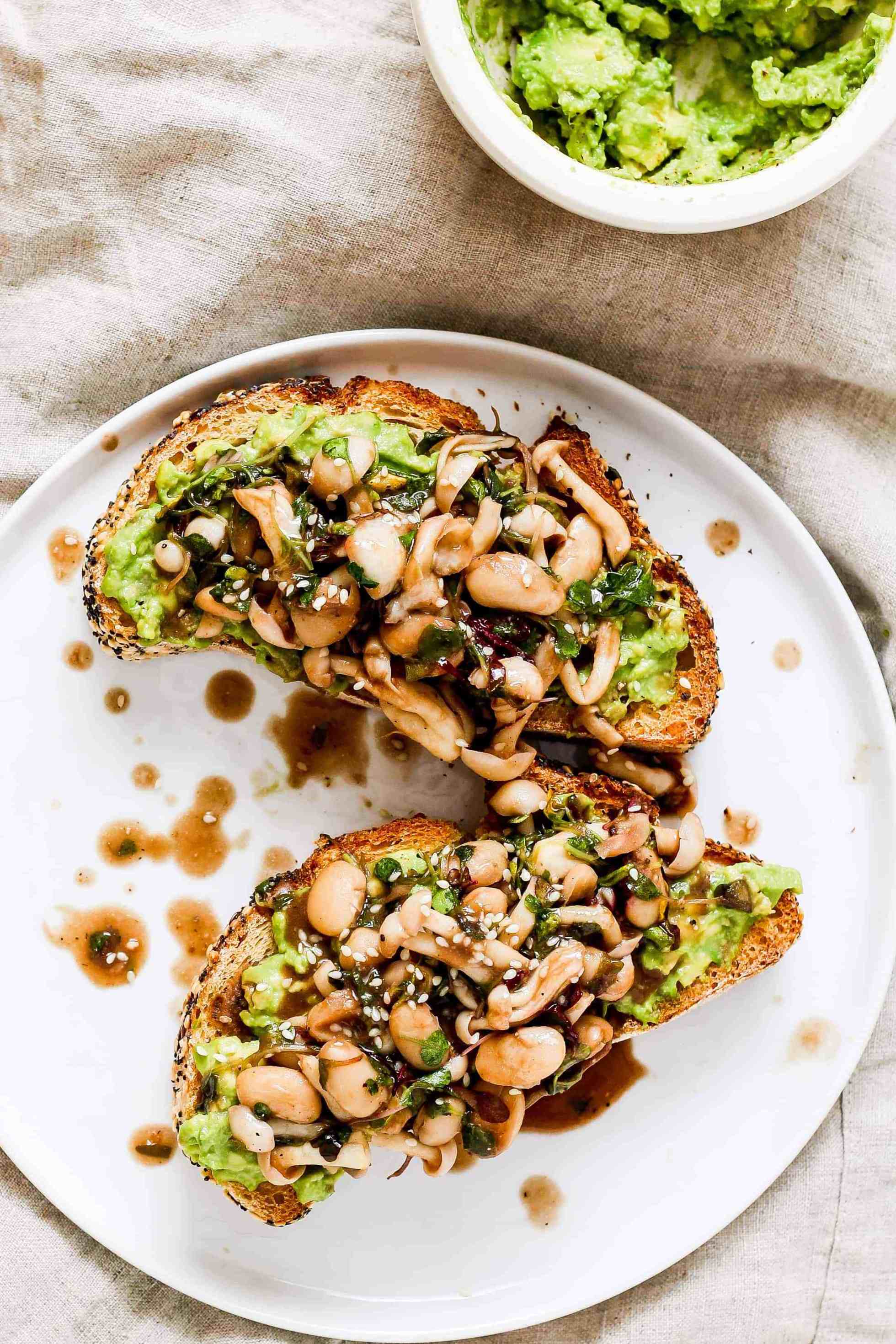 Avocado toast on a white plate topped with beans and mushrooms for easy college breakfasts 