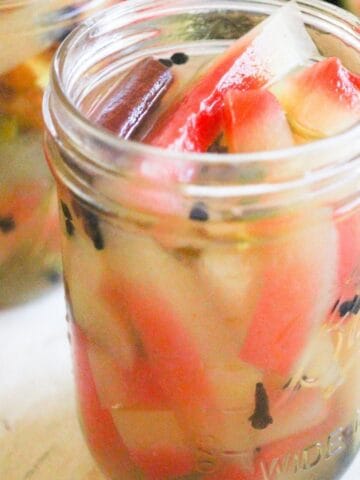Pickled watermelon rind with cinnamon and spices in a glass jar.