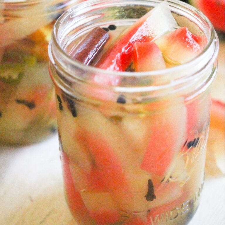 Pickled watermelon rind with cinnamon and spices in a glass jar.