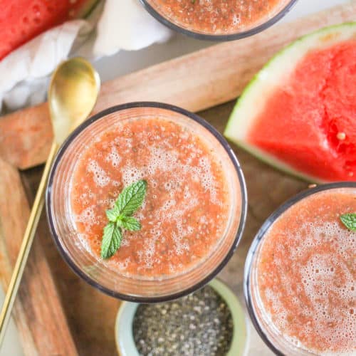Overhead image of Watermelon Chia Fresca in glasses on a wood tray with a gold spoon.