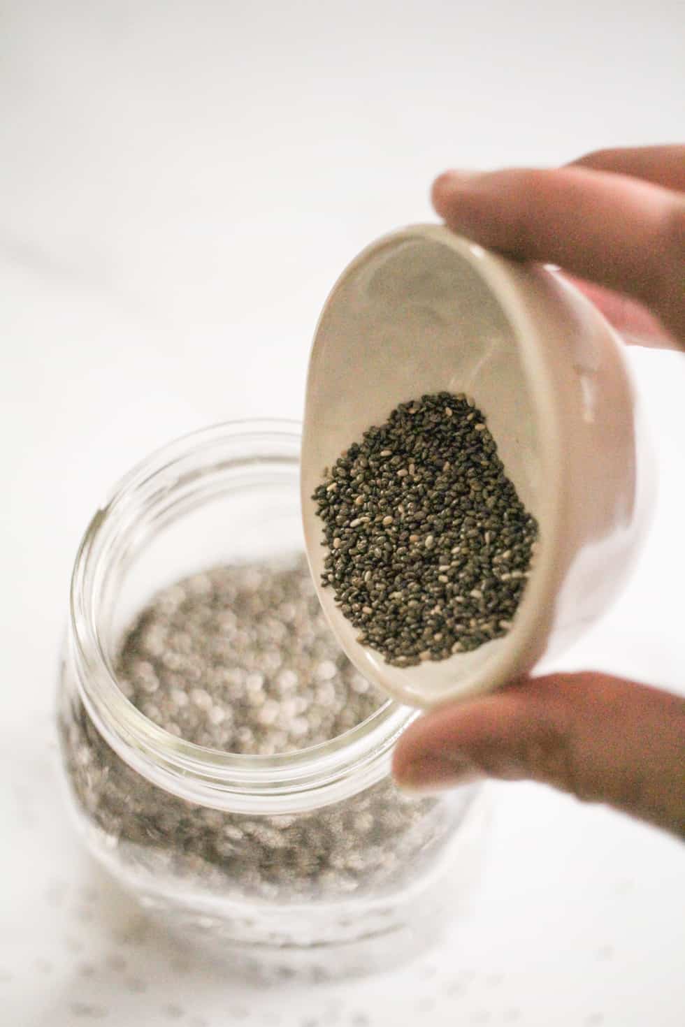 Pouring chia seeds into a jar of water.