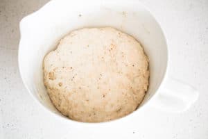 Pizza dough in a large white measuring bowl.